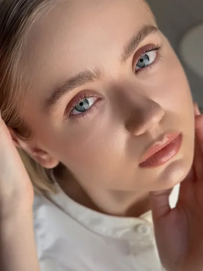 A close-up portrait showcasing the beautiful, natural-looking lift from a double lash lamination. Her blue eyes appear even more striking.