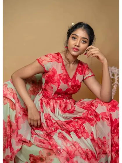 A seated portrait in the red floral organza gown, showcasing its vibrant print and flattering V-neckline. A perfect look for a modern romantic.