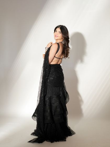 A full-length view of this incredible modern saree look. The makeup is kept soft and glamorous to balance the dramatic silhouette of the outfit.