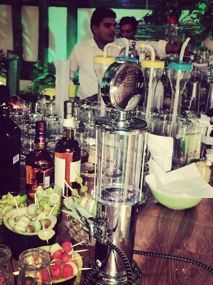 A wide view of a busy bar at a large event, featuring a gas pump-style drink dispenser and our team serving a crowd. This highlights our capacity for large-scale beverage catering.