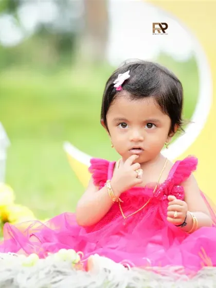 A close-up of the baby girl in the outdoor moon setup, looking thoughtfully at the camera. The soft, natural light is perfect for capturing her delicate features.