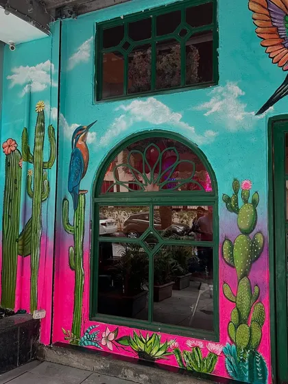 A Mexican-themed restaurant exterior I painted, featuring bright turquoise and pink walls with cacti and a kingfisher.