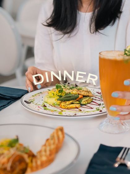 Dinner at my café is an elegant affair. Here, a guest is enjoying a beautifully plated main course with a refreshing iced tea.