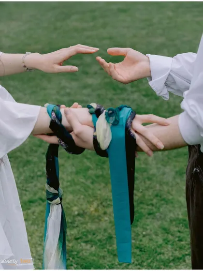 A close-up of the hand-fasting ritual, where ribbons bind their hands and hearts together. A powerful, symbolic detail from their unique commitment ceremony in Switzerland.