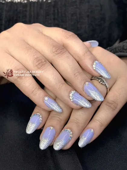 Icy and elegant. This design features a lavender base with a silver glitter gradient and is finished with a cascade of rhinestones at the cuticle for a frosted, sparkling effect.