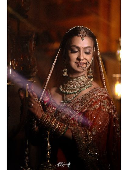 A bride holding a lamp, her face illuminated softly, creating a serene and traditional portrait.