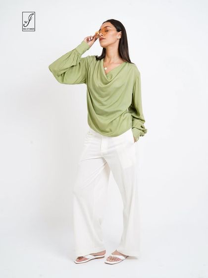 A pose that highlights the drape of the cowl neck and the flowy fabric of the top.