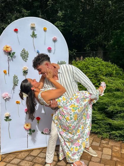 A happy couple enjoying a photo opportunity in front of a beautiful floral backdrop, perfect for a bridal shower or engagement party.