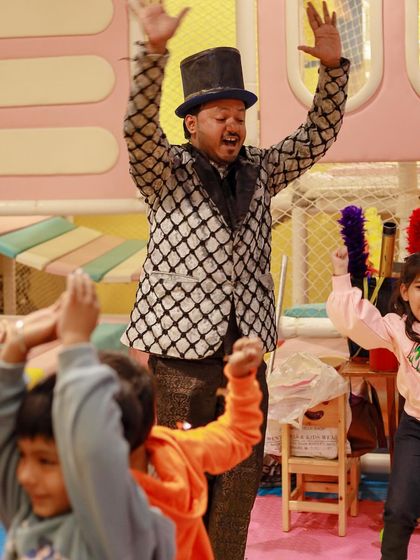 A magician and the kids raise their hands in excitement. Our entertainers are experts at creating a lively and interactive atmosphere.