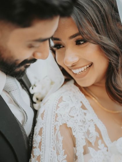 A close-up candid moment filled with smiles and intimacy. This portrait highlights the bride's delicate lace dress and the couple's joyful connection.