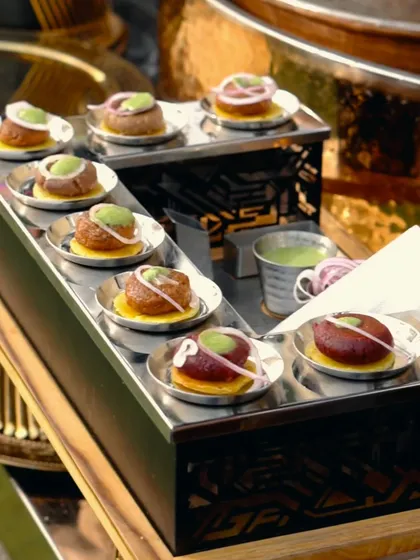Perfectly plated Galouti Kebabs, each resting on a small, crisp bread base and topped with mint chutney, showcasing an elegant serving style.