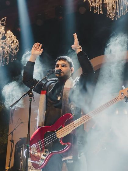 The bassist hyping up the crowd, surrounded by stage smoke and dramatic lighting.