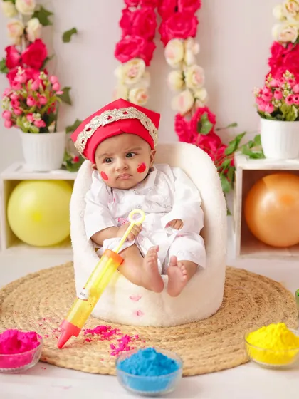 This little one looks ready to play Holi, holding a toy pichkari in our safe and fun studio environment.