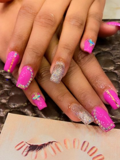 A vibrant set of hot pink square nails. The design is loaded with bling, including full rhinestone-covered accent nails and smaller crystal details on others.