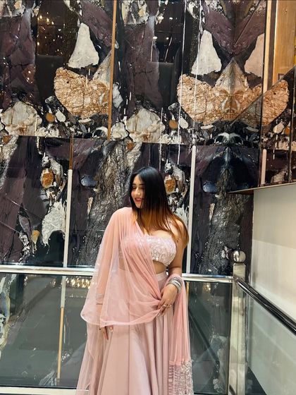 A soft, smiling pose in a delicate pink lehenga. This is a perfect look for a sangeet or engagement party.