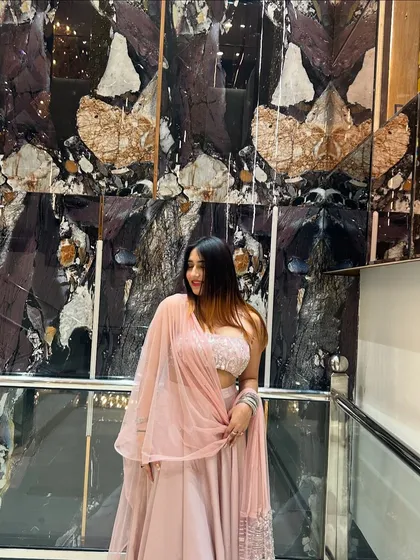A soft, smiling pose in a delicate pink lehenga. This is a perfect look for a sangeet or engagement party.