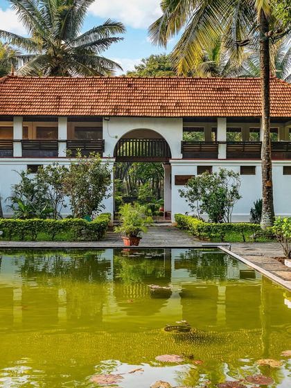 The Padipura, a beautiful Kerala heritage building, reflected in the calm waters of the pond. This tranquil space is dedicated to yoga, meditation, and quiet reflection for our guests.