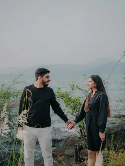 A beautiful shot of the couple holding hands and looking at each other across a natural landscape. The composition feels balanced and serene, telling a story of partnership.
