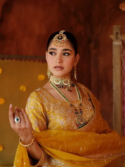 A powerful, regal pose. The makeup is strong and defined, creating a high-fashion look.