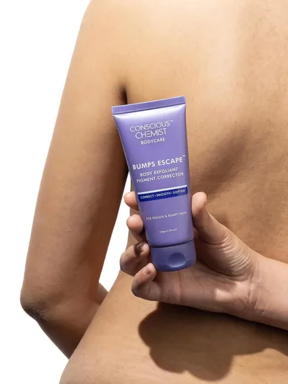 This shot focuses on the product in context. The model holds the body exfoliant against her back, suggesting its use case in a subtle and aesthetic way. The clean white background keeps it from being distracting.