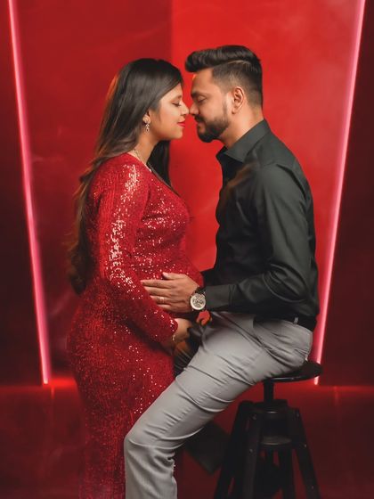 An intimate forehead-to-forehead pose, creating a powerful silhouette of connection against a vibrant red background.