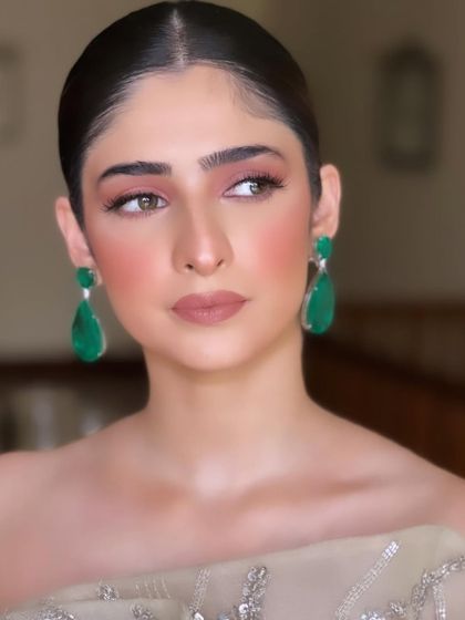 A close-up of a soft, peachy-pink makeup look with a sleek bun. This is a perfect example of elegant party makeup.