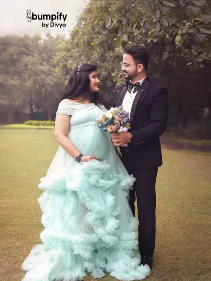 A lovely couple's portrait from an outdoor session, with the mom-to-be in a light blue ruffled gown. The dad-to-be is dressed in a sharp tuxedo, creating a formal yet natural look.