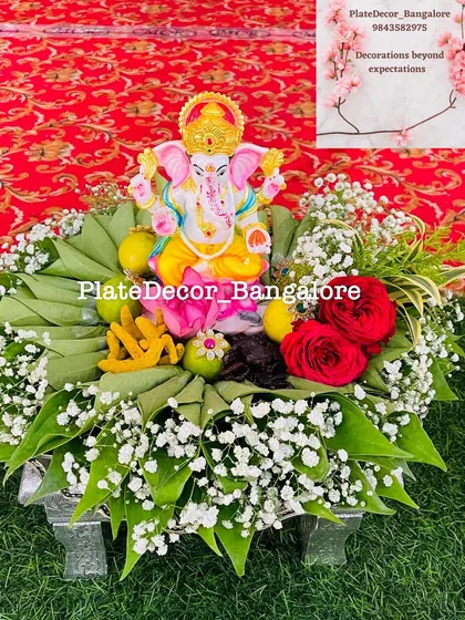 A sacred pooja platter featuring a Lord Ganesha idol, surrounded by carefully folded betel leaves, fresh flowers, and other holy items. I design these platters to bring a sense of devotion and beauty to your religious functions.