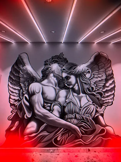 The final angelic couple mural, illuminated by dramatic red lighting. The monochrome painting style allows it to be transformed by colored lights, changing the mood of the room.