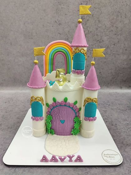 A fairytale Princess Castle cake. This beautiful design features towers, a rainbow, and a lovely floral door, perfect for any little princess.