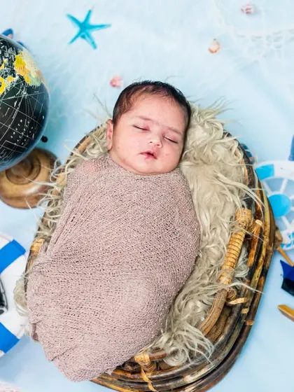 A newborn baby is the center of this traveler-themed setup, complete with a globe, camera, and other nautical props.