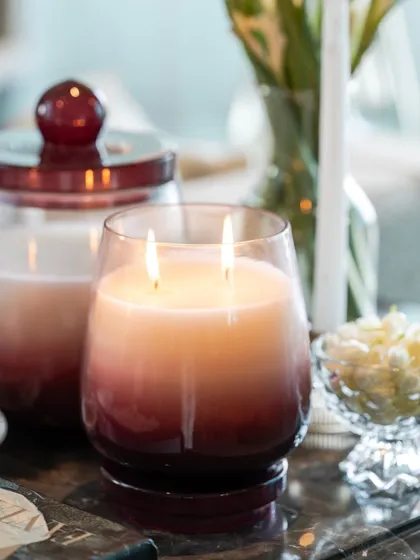 A close-up of my two-wick Opulent Oud candle. The ombre glass glows from within, creating a warm and soothing ambiance that is both luxurious and comforting.