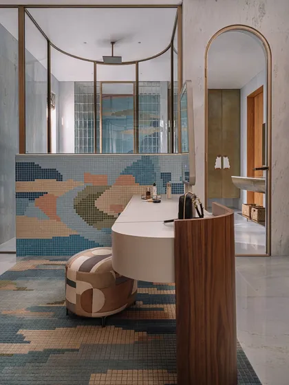 In this master bathroom, we collaborated with our partners to create a stunning mosaic tile rug that mimics the patterns on the wall. The space also features a brass-clad linen closet with custom marble handles, adding a layer of warmth and opulence.