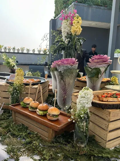A sneak peek of one of our winter lunch setups on a rooftop. The spread includes mini sliders, bruschetta, and pizzas, all beautifully arranged with fresh flowers and greenery.