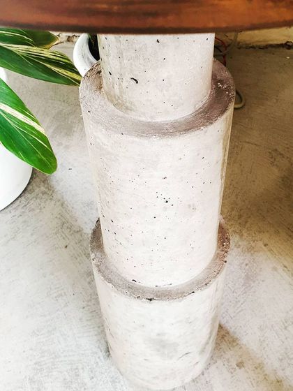 We love experimenting with materials. This is a close-up of a stacked concrete base for a side table, showcasing the raw, industrial texture of the material.