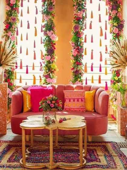 A vibrant and colorful seating area for a Mehndi function. I used bright pink furniture, floral pillars, and tassel curtains to create a lively and photogenic corner.