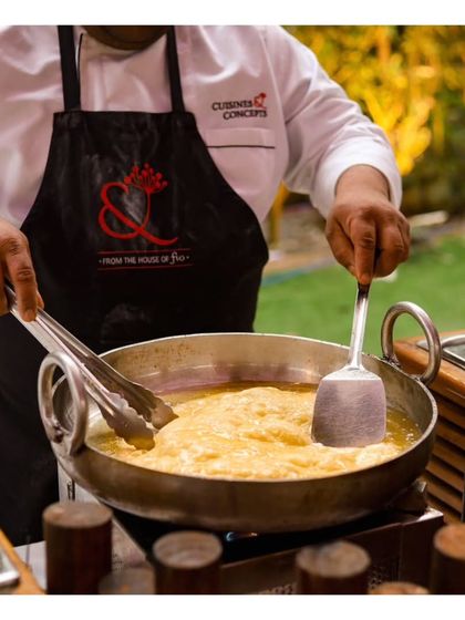 A chef deep fries bread in a large kadai, a classic preparation for many Indian dishes. This action shot captures the authentic cooking techniques we employ for our traditional cuisine offerings.