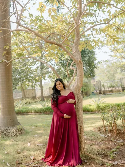 A beautiful smile from a mama-to-be, feeling radiant and joyful in her flowing red gown during this garden maternity shoot.