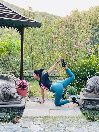A variation of Tiger Pose, this deep stretch opens the hips and spine. Practicing in a garden surrounded by flowers reminds us that yoga can be done anywhere, not just on the mat.