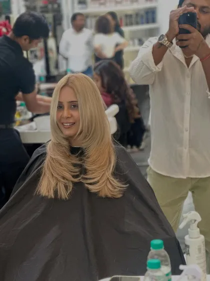 A happy client with her new sleek, blonde hair. The color is a beautiful, even shade of light blonde.
