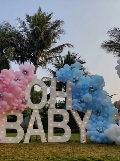Make a big statement with an outdoor celebration. For this gender reveal, we used large, illuminated "OH BABY" marquee letters flanked by pink and blue organic balloon clouds. This setup creates a spectacular photo opportunity and focal point for your event, day or night.