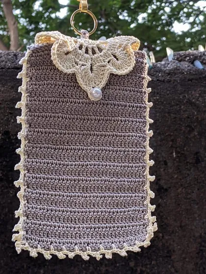 We can add beautiful details like this lace-style flap and a pearl button to our phone pouches. This one is shown in a lovely grey with a cream-colored trim.