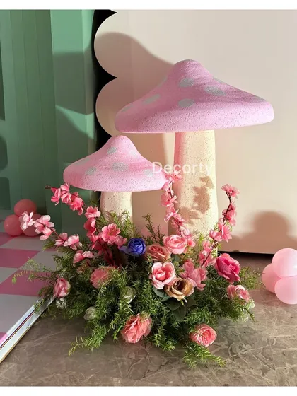 Hand-crafted mushroom props surrounded by flowers add to the enchanted forest feel of this Wonderland party.