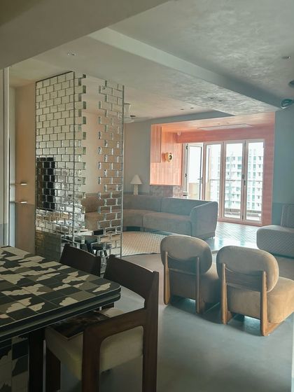 The living space in this eclectic apartment, where a mirrored brick partition and a custom tiled dining table create a unique, layered look.