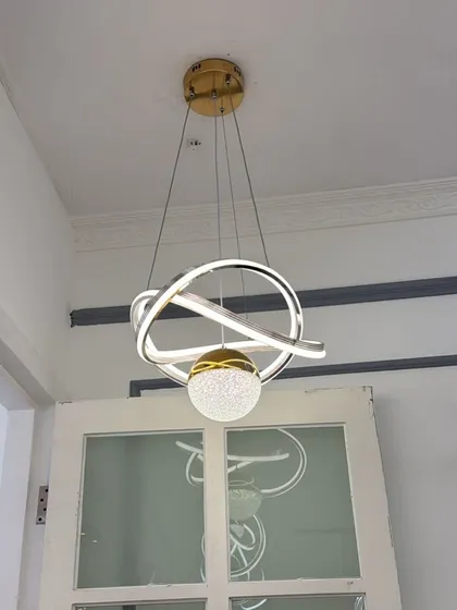 A modern pendant featuring interlocking rings and a central crystal-dusted sphere. A compact yet eye-catching design.
