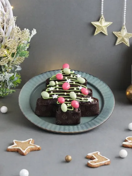 A fun and festive Christmas tree-shaped plum cake, decorated with colorful candies, perfect for holiday parties.