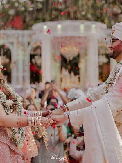The couple holding hands, surrounded by guests, after the Varmala.