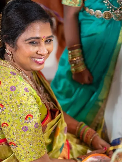 A smiling mother of the bride in her custom-designed lime green blouse. The colorful floral embroidery adds a joyful touch to her look.