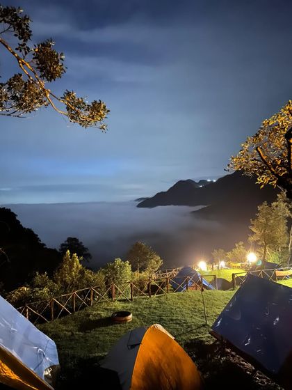 The campsite at twilight, with lights on and clouds filling the valley, creating a serene and magical atmosphere.