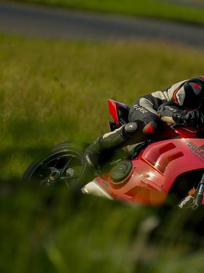 A rider on a red Ducati Panigale seen through the grass, highlighting the different perspectives our professional photographers capture.